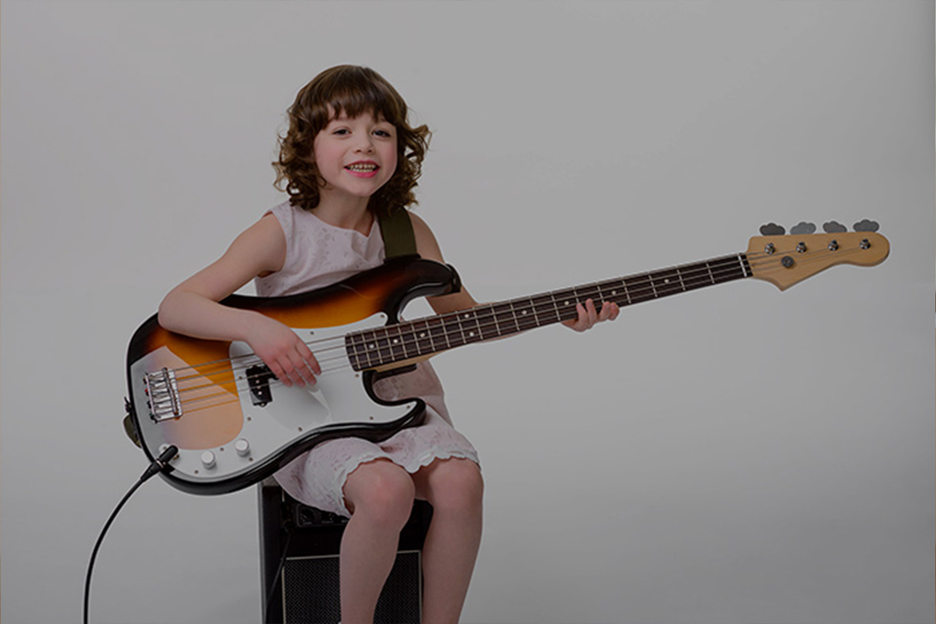 A kid sitting playing bass guitar