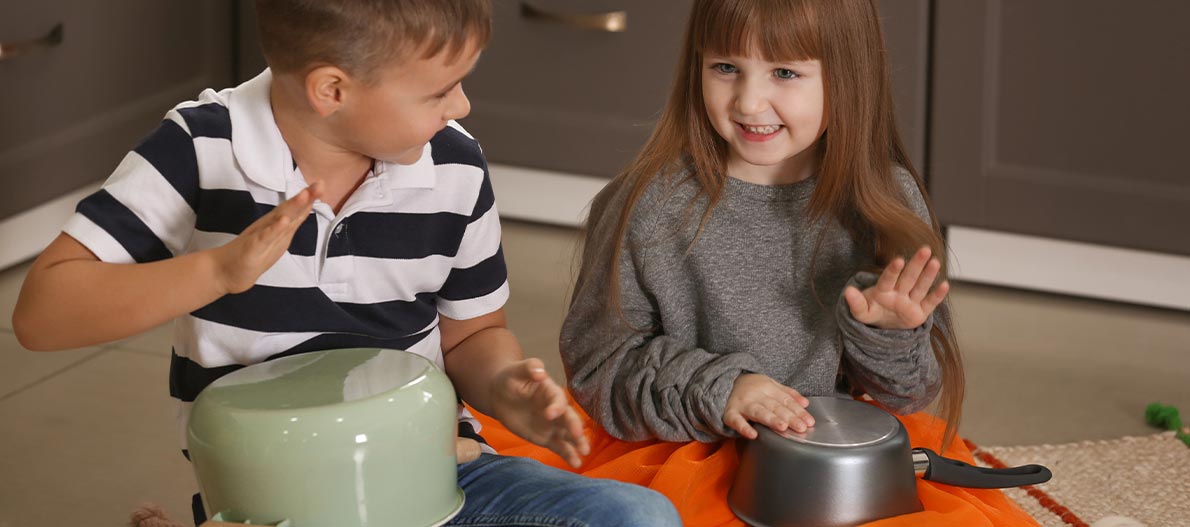 A boy and a girl playing and tapping pots as drums