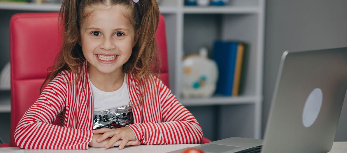 Girl smiling sitting on the table with laptop
