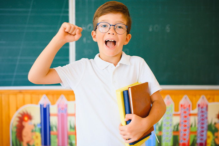 Happy boy with glasses and books in hand