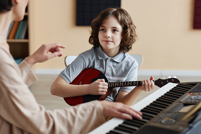 Boy listening to his piano playing teacher