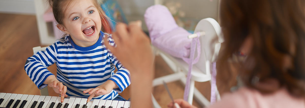 Girl playing keyboard with teacher in home