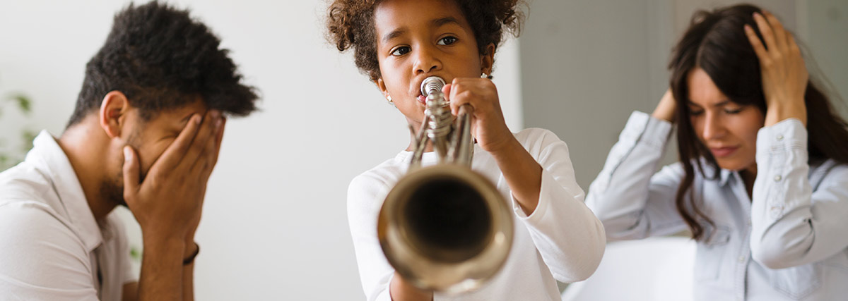 Parent covering themselves for child playing trumpet