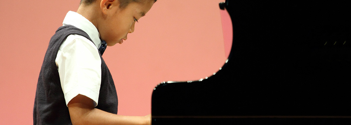 Asian boy playing piano on stage