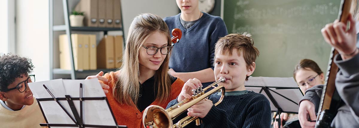 Children learning different instruments with a supportive music teacher