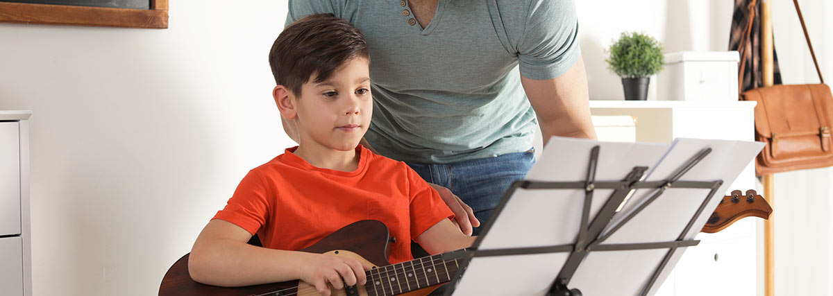 Father helping young child choose guitar as a suitable first musical instrument
