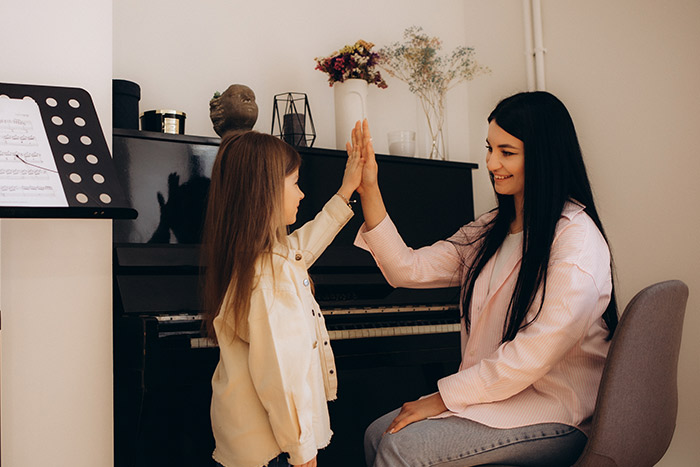 Woman and girl giving high five near piano