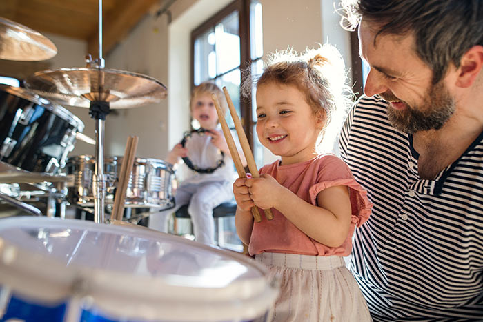 Young child exploring drums with parent support during early music learning
