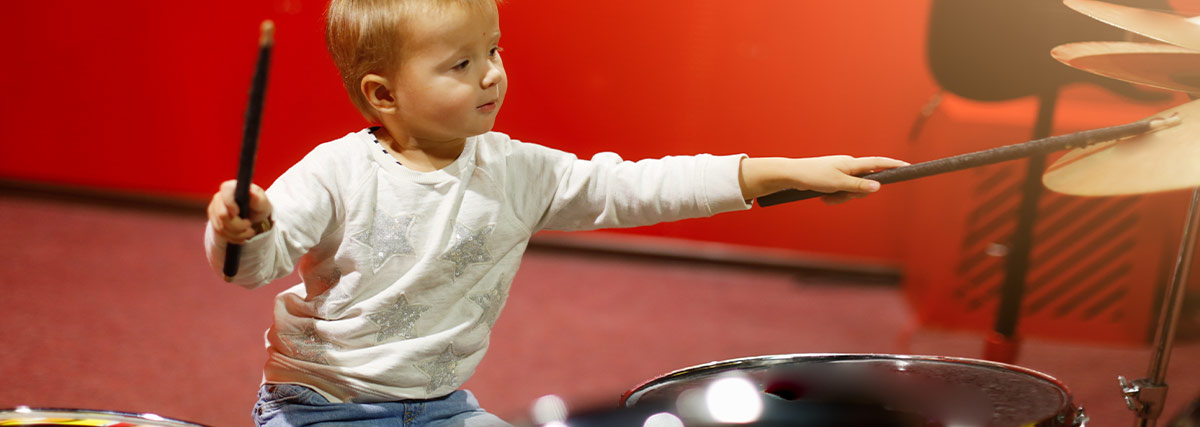 Young child playing drums and developing rhythm focus and coordination