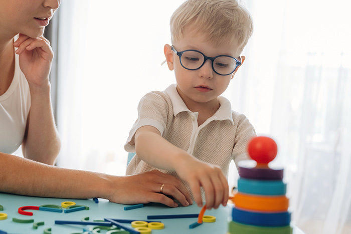 Mother supporting a young child during a colourful cognitive learning activity