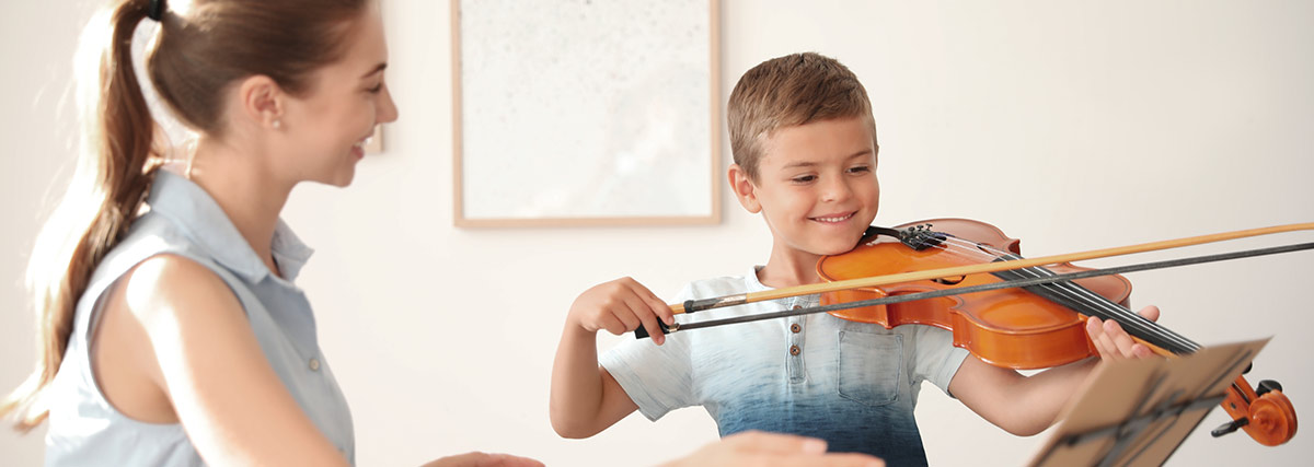 Young child learning violin with a supportive music teacher