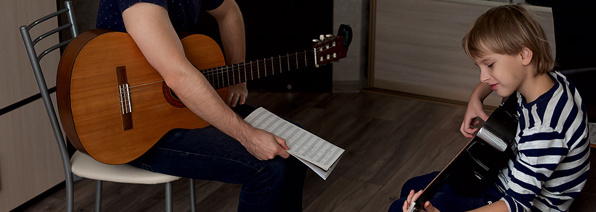 Young student trying guitar with a music teacher