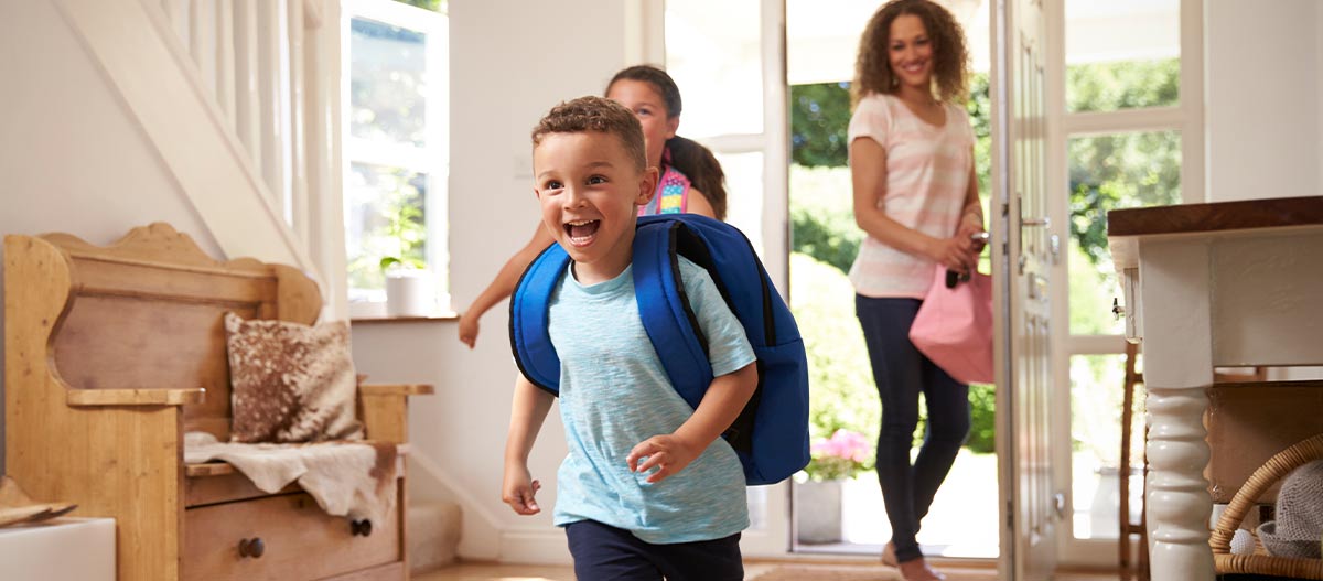 Happy children arriving home from school ready for their after school routine