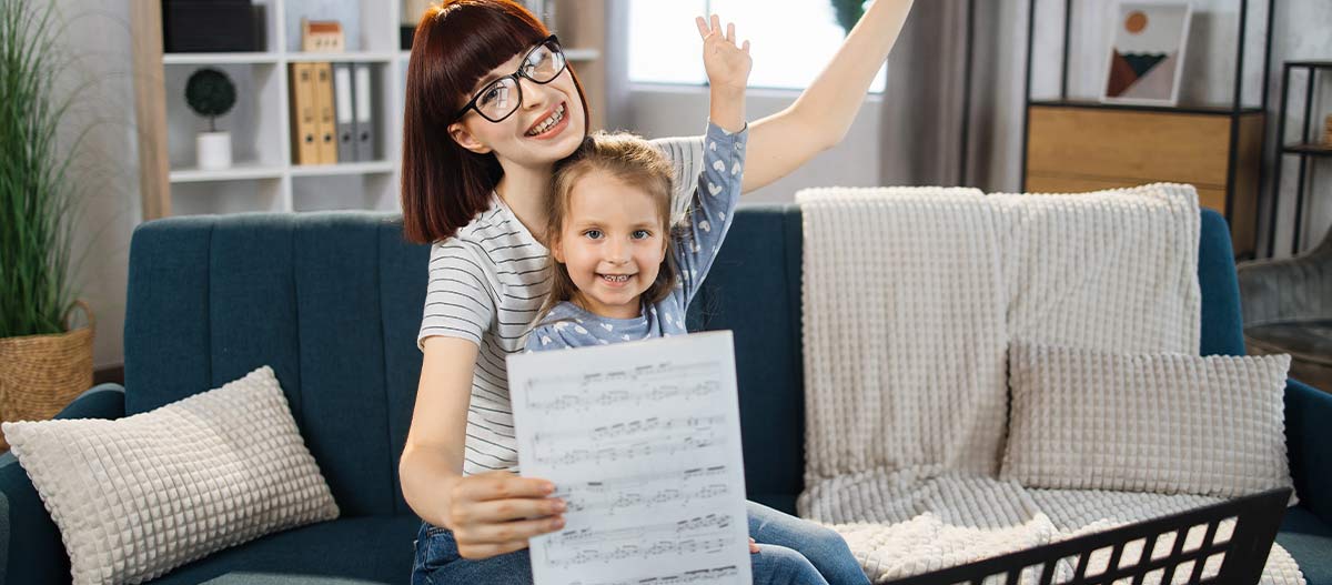 Mother celebrating her daughter’s progress during piano practice at home