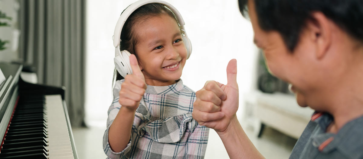 Parent encouraging a smiling child during piano practice at home