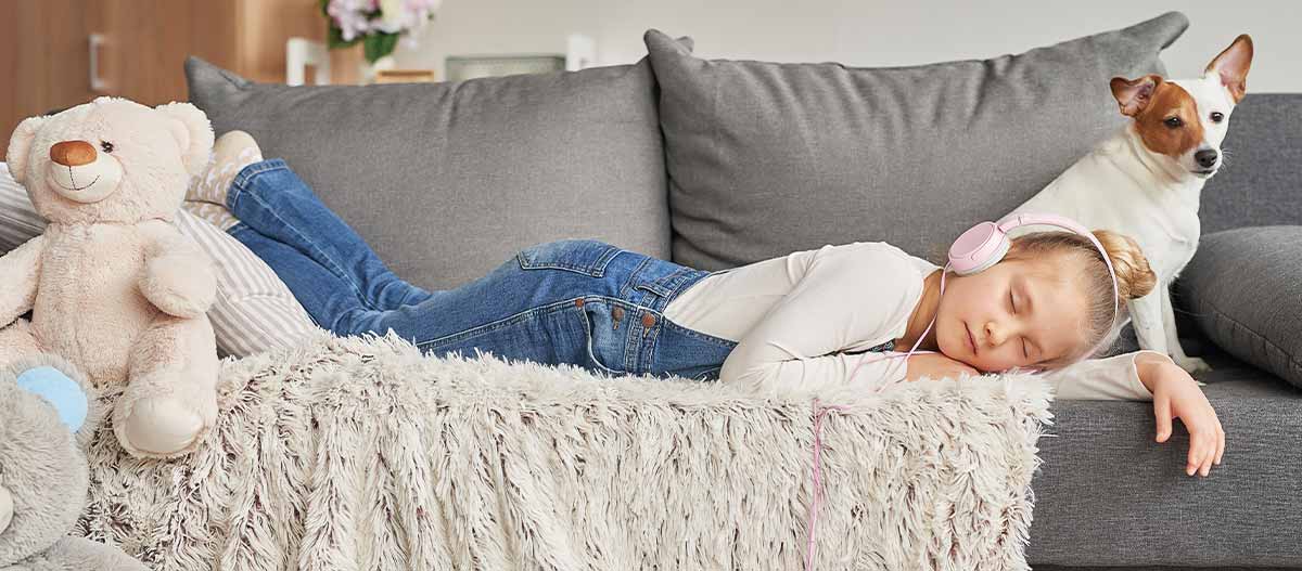 Tired schoolgirl resting at home while listening to music