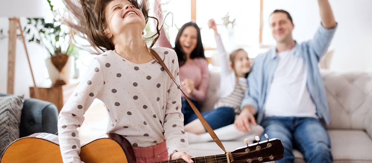 Young girl enjoying guitar and music with her family at home